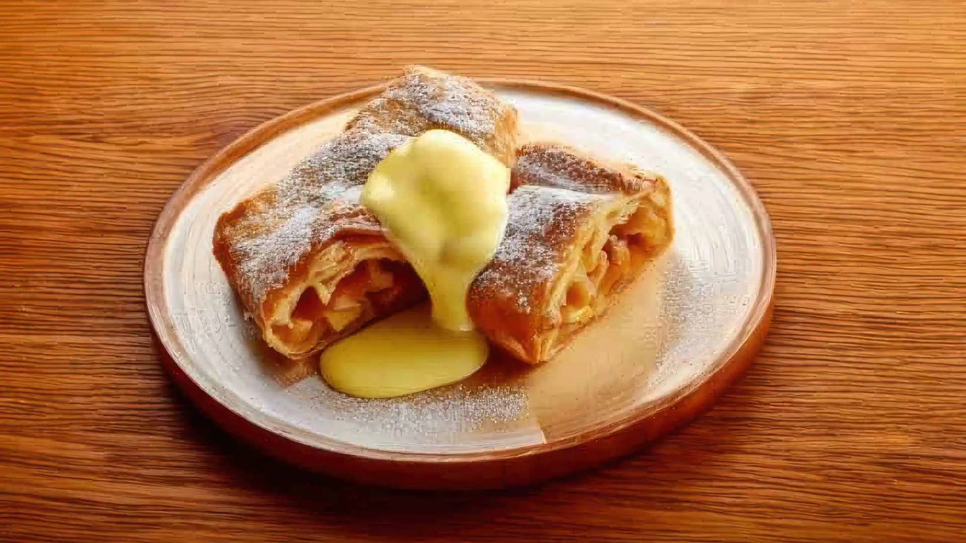 La Scarpetta Ristoranze Pizzeria Dornbirn Firefly Apfelstrudel mit Vanillesauce auf einem Buchenholztisch 54632 topaz high fidelity v2 1920w
